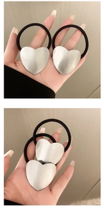 Detail showing two elastic hair ties with matte silver brushed heart-shaped metal charms
