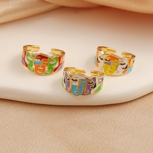 Three gold-plated open rings with colorful enamel abstract face designs on silk