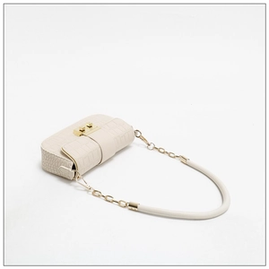 Detailed close-up of beige crocodile pattern handbag with gold chain strap