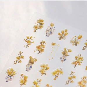 Detailansicht der zarten gelben Blumen und Teekannen-Muster der Nageltattoos