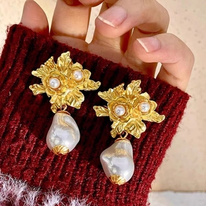 Détail de boucles d'oreilles fleurs dorées vintage avec perles baroques sur fond rouge