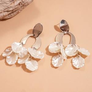 Detail of silver drop earrings with layered pearlescent acrylic petals on a soft background