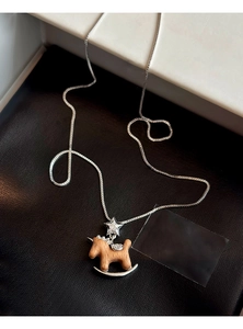 Détail macro du pendentif cheval à bascule avec étoile en zircon sur fond en cuir noir