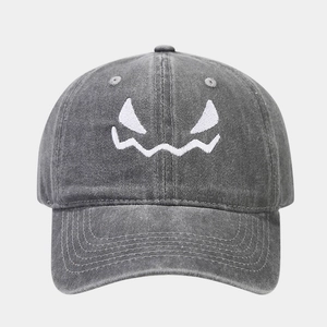 Détail de la broderie fantôme blanche sur une casquette en coton délavé gris foncé style vintage