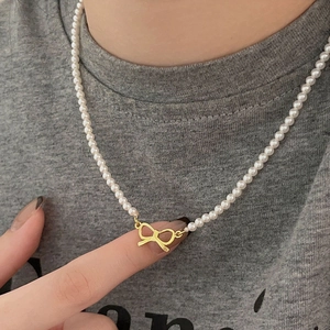 Close-up of a 925 silver pearl necklace with a delicate gold hollow bow pendant detail