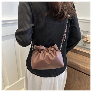 Detail of coffee brown pleated cloud bag with silver chain strap and metal ball