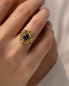 Dettaglio di un anello in acciaio inossidabile dorato con una gemma nera su un modello