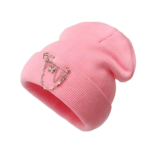 Detailed macro shot of a pink knitted beanie featuring a silver butterfly and chain charm