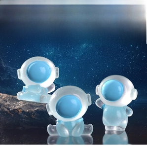 Detailed view of three translucent resin astronaut figurines in cosmic scenery