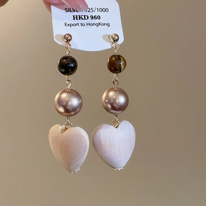 Detailed macro view of heart-shaped drop earrings with tiger eye and 925 silver studs