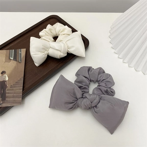 Close-up of Morandi colored cotton bow scrunchies in white and grey on a wood tray
