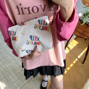 Close-up of white corduroy pouch with Keep Smiling text and yellow smiley face print