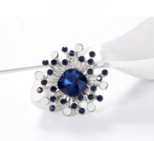 Macro detail of geometric vintage brooch with deep blue crystal and radiant silver inlay