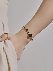 Detailansicht eines Vintage-Goldarmbands und Ringsets mit smaragdgrünen Edelsteinen