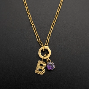 Close-up of gold paperclip chain necklace with textured letter B and purple gem