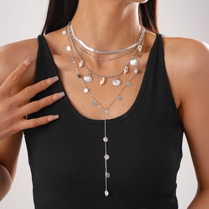 Detail eines silbernen mehrlagigen Halsketten-Sets mit Muschel-Anhängern und Boho-Ketten