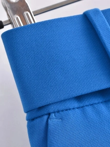 Detalle macro de la costura y la trabilla del cinturón en pantalones azules de tiro alto
