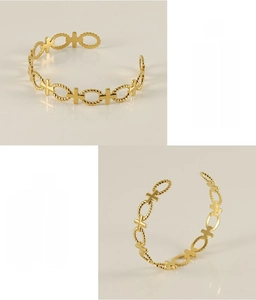 Detail of gold-plated stainless steel cuff bracelet with hollow cross and rope design