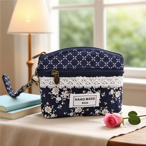 Detail of a dark blue floral coin purse with white lace and bronze zipper on beige cloth