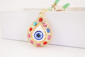 Detailed close-up of a golden teardrop Evil Eye pendant with colorful rhinestones