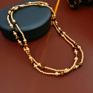 Detail of double-layer long necklace with golden pearls and tiger eye stone beads