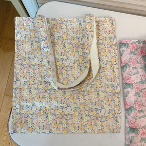 Close-up of a floral canvas tote bag with yellow and blue flowers and cream handles
