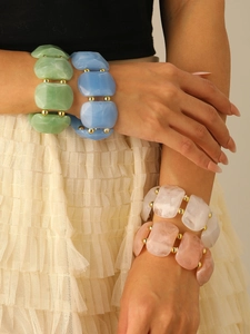 Nahaufnahme klobiger Harzperlenarmbänder in Pastellfarben mit goldenen Metallelementen