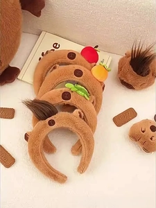 Detail of Capybara plush headbands featuring cute apple, orange and sprout decorations