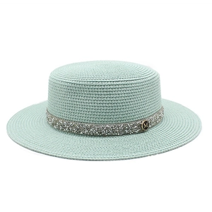 Detailed texture of mint green straw boater hat with shimmering ribbon and M logo