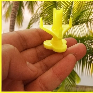 Portable yellow plastic pizza saver tripod stand held by hand in tropical background