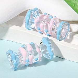 Detalle de cuentas de vidrio hechas a mano con forma de caramelo y rayas rosa y azul