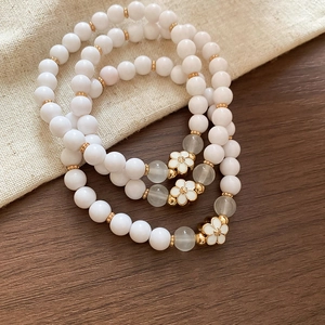Detailed macro view of acrylic beaded bracelets with white enamel flower pendants