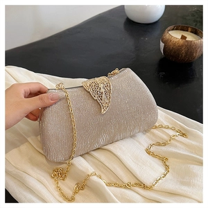 Close-up of champagne gold box clutch featuring sparkly wavy texture and leaf clasp