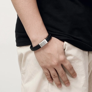 Close-up of black braided leather bracelet with silver magnetic steel clasp on wrist