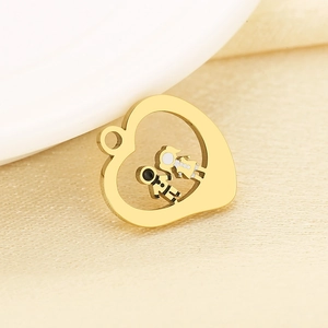 Macro shot of gold stainless steel heart pendant with boy and girl figures on beige fabric