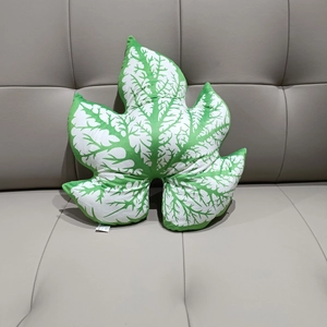 Detailed view of leaf-shaped plush pillow with realistic green vein patterns on a sofa