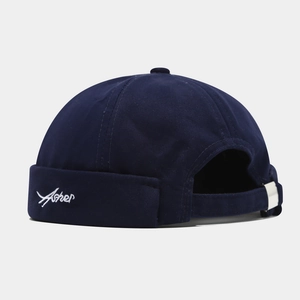 Detailed view of navy blue docker hat with white Asher embroidery and metal buckle