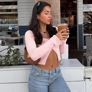 Close-up of pink long-sleeved cropped knit cardigan with button detail and blue jeans