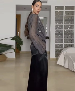 Detailed view of women's V-neck sequined long sleeve top with elegant black satin skirt