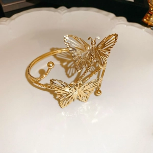 Close-up of golden hollow butterfly metal bracelet on elegant white relief porcelain plate