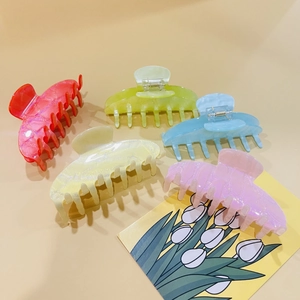 Detail view of five colorful large acrylic shark hair claws on a floral card