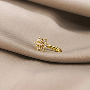 Macro shot of gold floral nose cuff with shimmering cubic zirconia on soft silk background