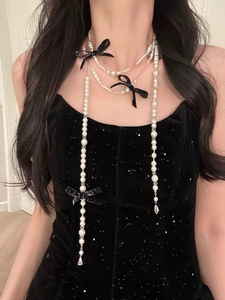 Detail of layered pearl necklace with black glitter bows on elegant black velvet dress