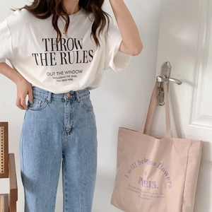 Detailed shot of white cotton canvas tote bag with black embroidered letter slogans
