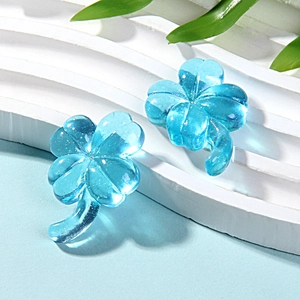 Macro shot of two blue transparent resin clover charms with bubble texture on white base