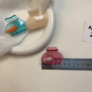 Fish-shaped acrylic hair claws in blue, cream and rose pink with a measuring ruler