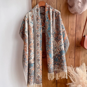 Detail of bohemian paisley scarf with tassels hanging on a wooden door in home setting