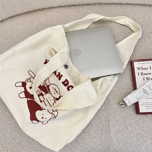 Détail du sac fourre-tout en toile montrant la capacité pour ordinateur et bouton pression