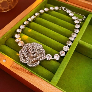 Détail d'un pendentif fleur argentée avec cristaux sur un coussin en velours vert