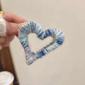 Detailed view of a handmade blue heart plush hair claw clip with woven texture